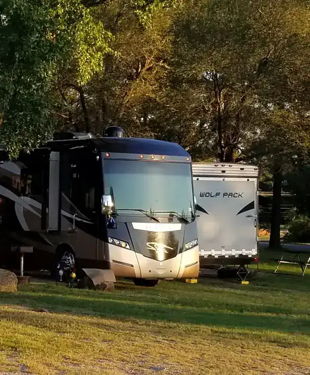 A motorhome and a fifth-wheel on their sites in golden-hour light